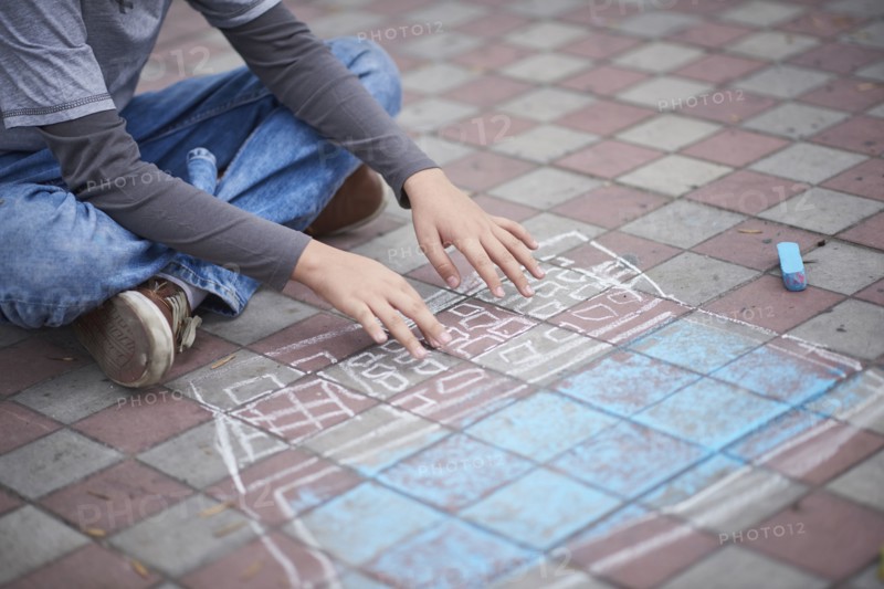 Hispanic boy typing on chalk laptop on sidewalk