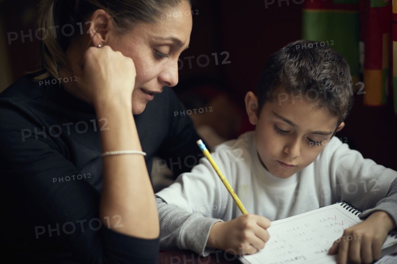 Hispanic mother watching son practicing writing alphabet