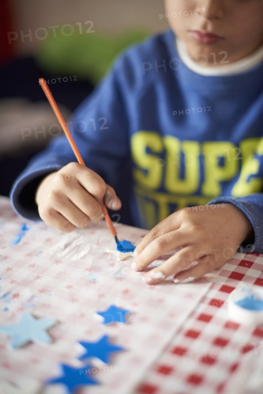 Hispanic boy painting stars at table