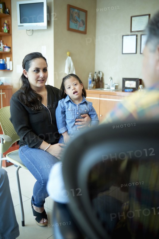 Hispanic mother and daughter with Down Syndrome talking to doctor