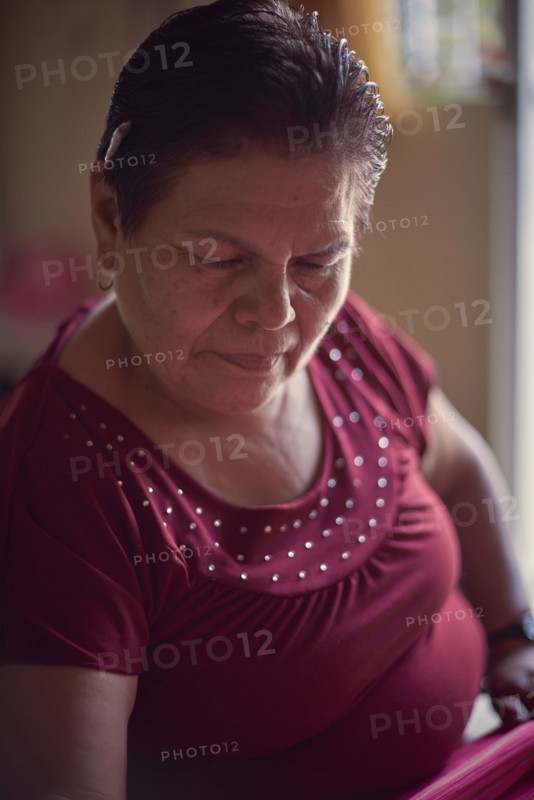 Hispanic woman weaving fabric on loom