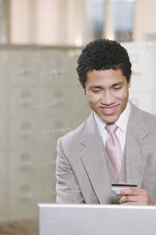 Mixed race businessman with laptop holding credit card