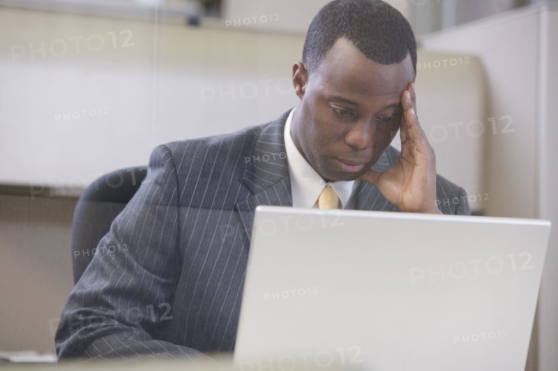 Stressed African businessman working on laptop