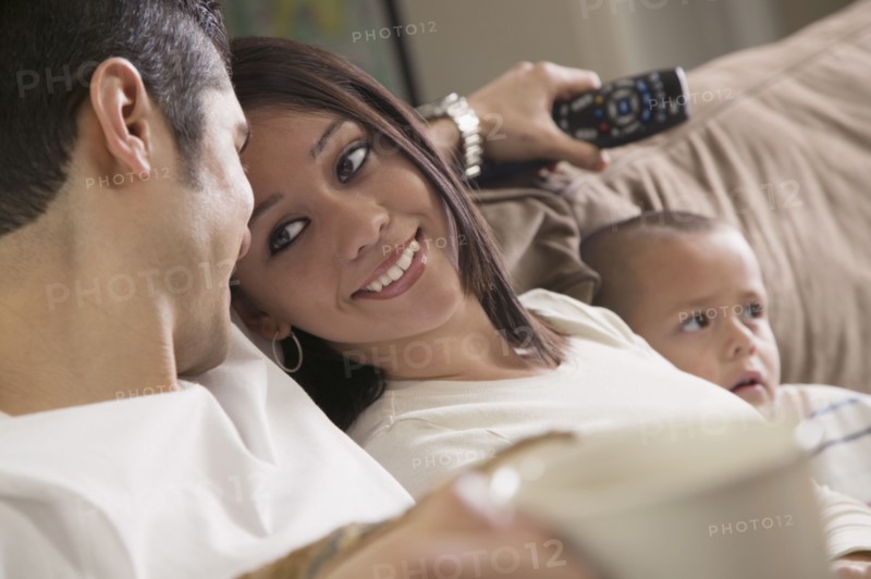 Hispanic couple and son relaxing on sofa