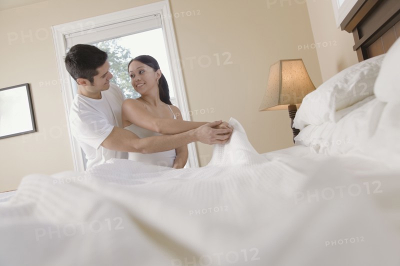 Hispanic couple making bed