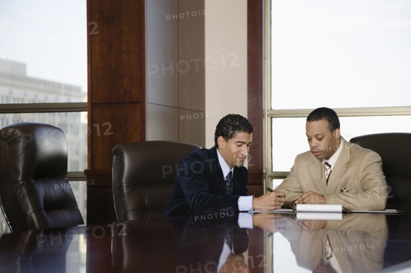 Two businessmen working in executive conference room