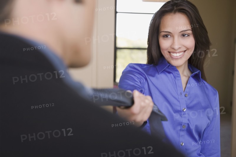 Hispanic woman leading husband into the bedroom