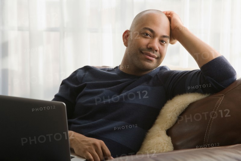 Mixed race man sitting in chair with laptop