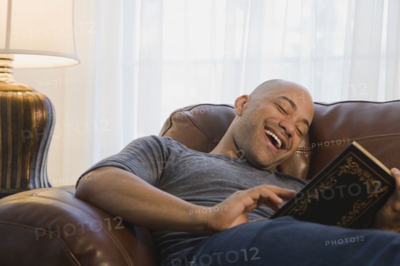 Mixed race man in armchair reading book