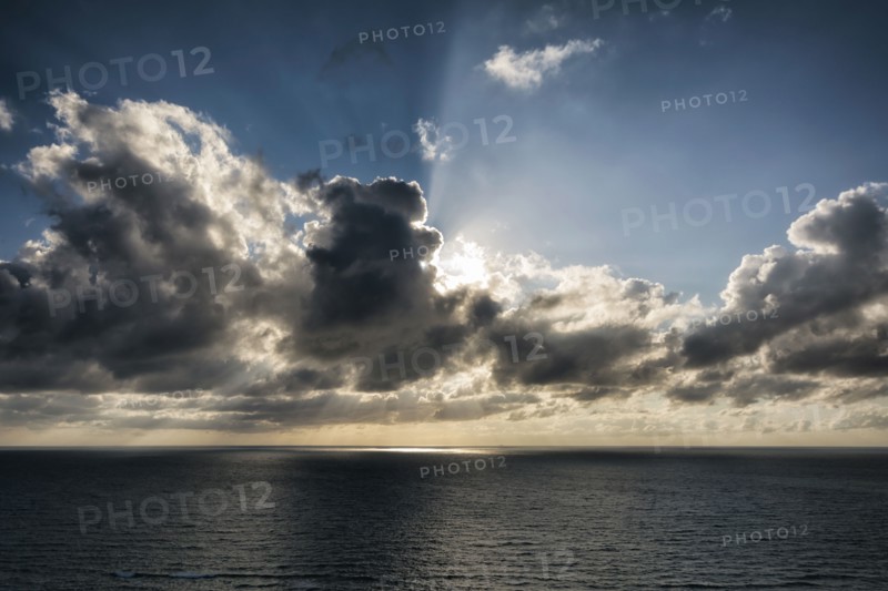 Sunbeams behind clouds over ocean