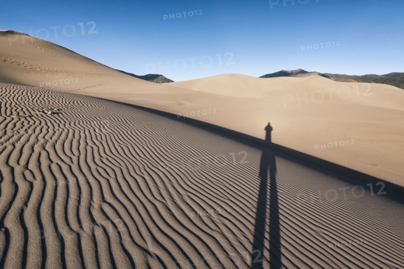 Shadow of person on sand dunes