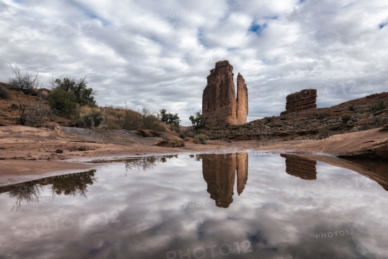 Reflection of rock formation and clouds in puddle