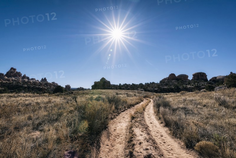 Sun in blue sky over desert path