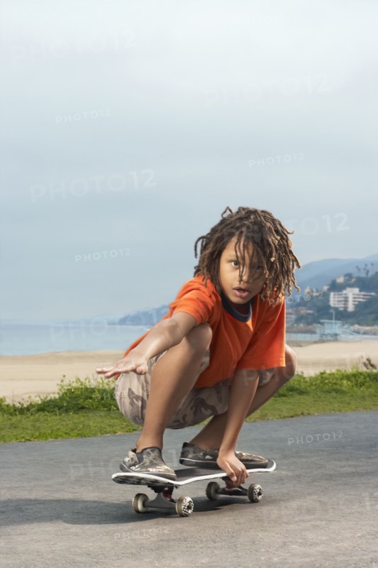 Mixed Race boy riding skateboard