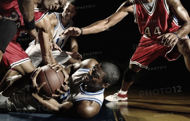 Multi-ethnic basketball players struggling for basketball