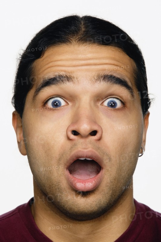 Close up studio shot of Hispanic man looking surprised