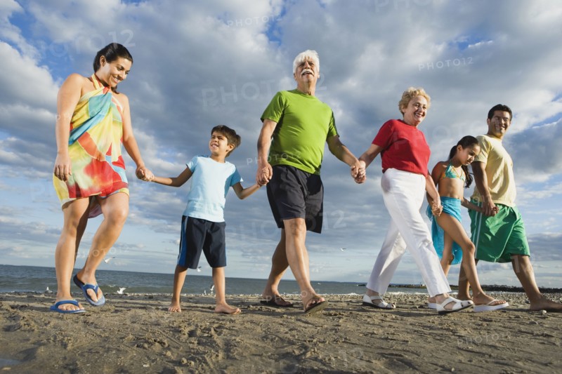 Low angle view of Hispanic family holding hands at beach
