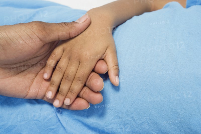 Close up of African boy holding parent's hand