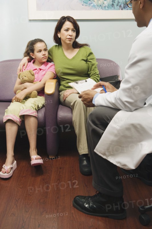 Doctor talking to Hispanic mother and daughter in waiting room