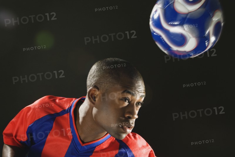 African American man bouncing soccer ball on head