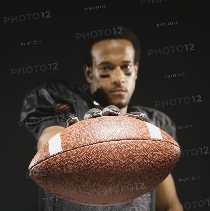 African American male football player holding out football