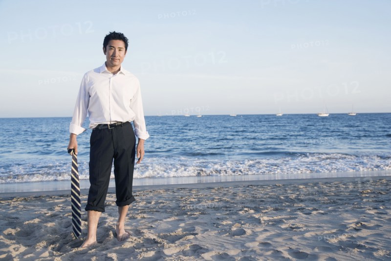 Asian businessman standing on beach