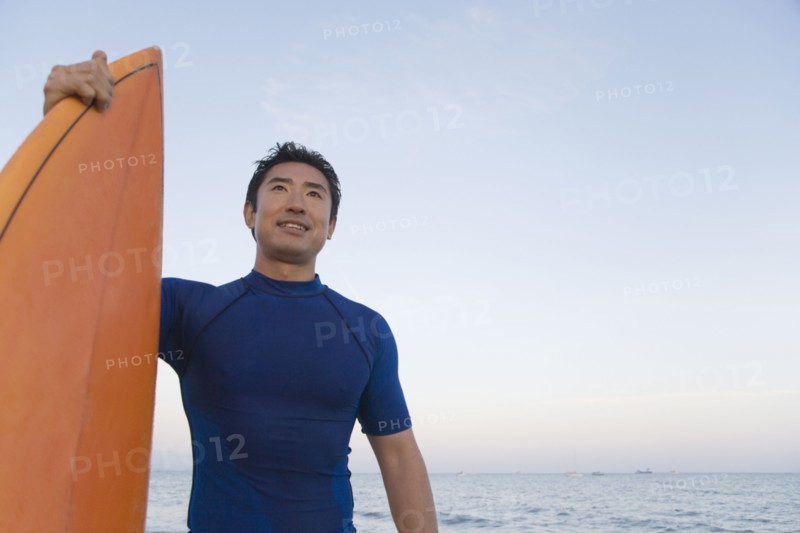 Asian man holding surfboard