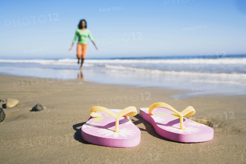 Flip-flops on beach in front of woman