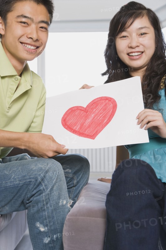 Chinese couple holding paper with heart