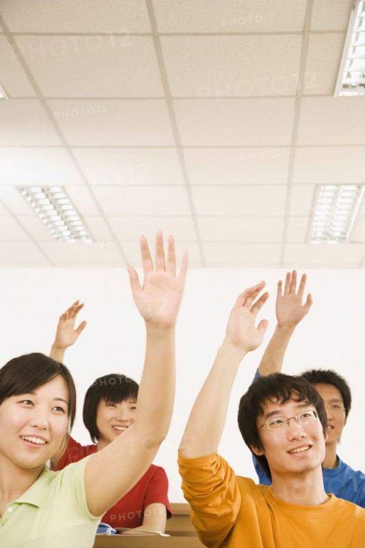 Chinese students with arms raised in classroom