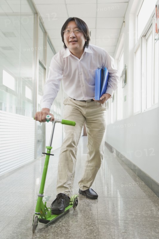 Chinese man riding scooter in corridor