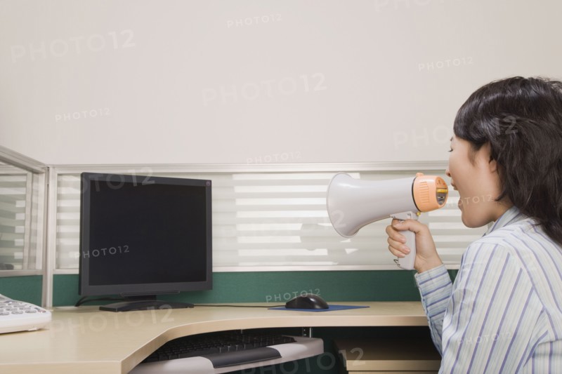 Chinese businesswoman yelling at computer through megaphone
