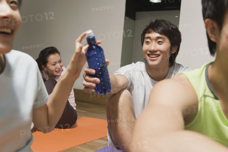 Chinese man handing woman water bottle in exercise class