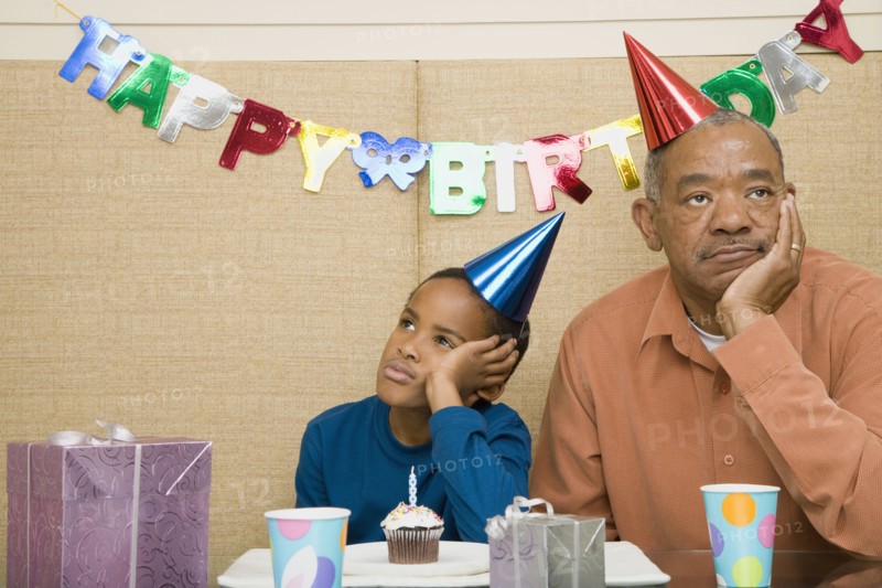 African boy with grandfather and cupcake at birthday party