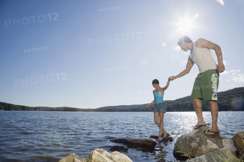 Father and daughter standing by lake