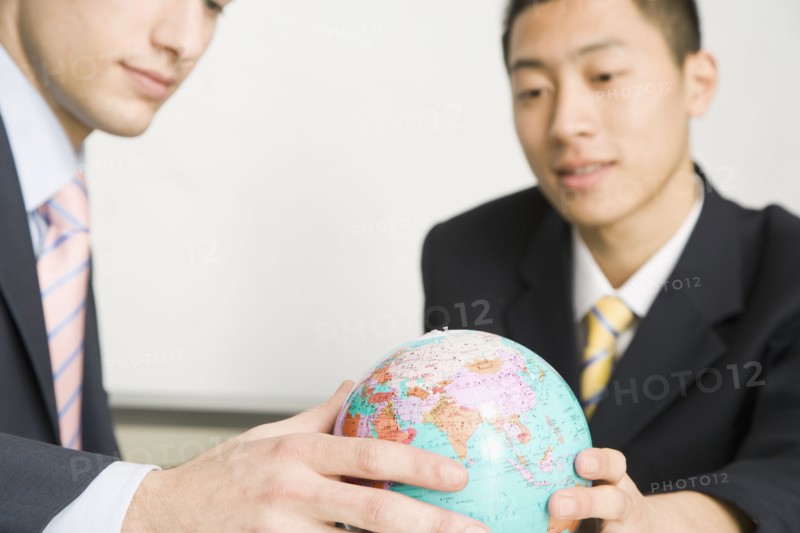 Businessmen looking at small globe