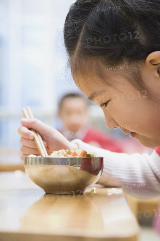 Chinese girl looking at food in bowl