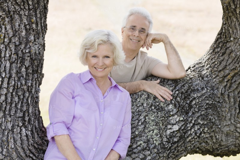 Caucasian couple leaning on tree