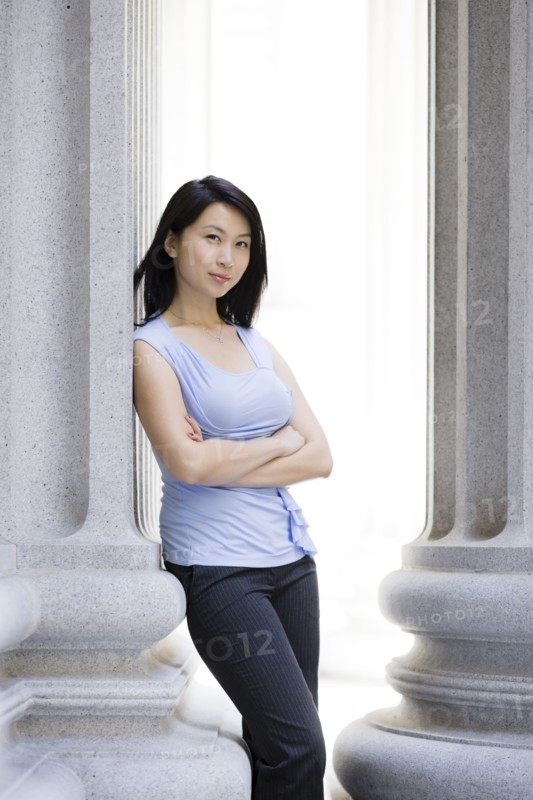 Chinese businesswoman leaning against stone pillar