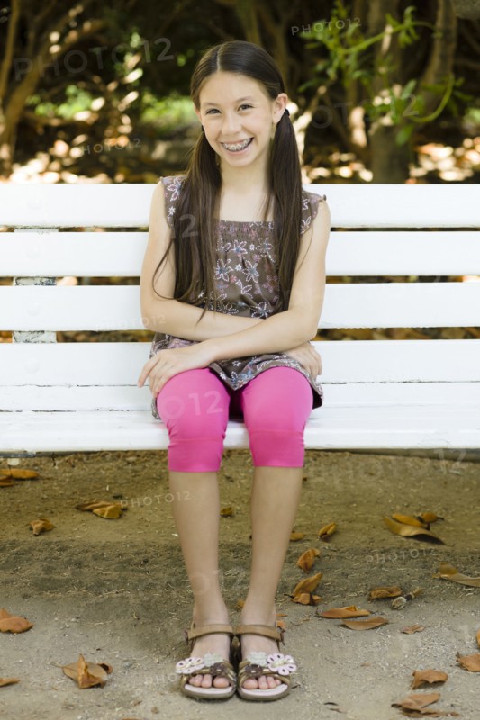 Smiling mixed race girl sitting on park bench