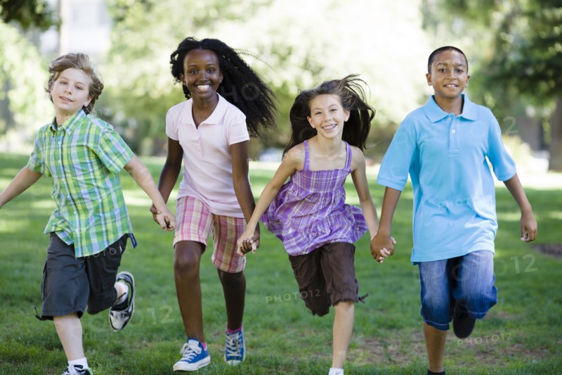 Happy children holding hands and running in park