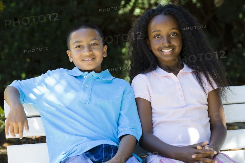 Smiling children sitting on park bench