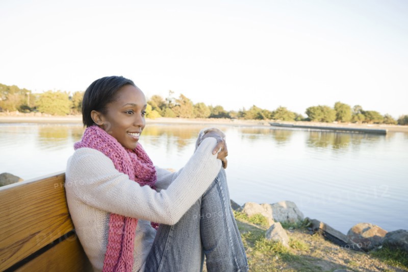 Woman sitting on bench near shore
