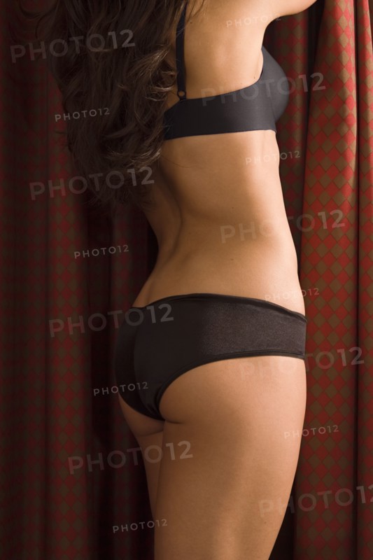 Semi-nude woman standing next to curtains