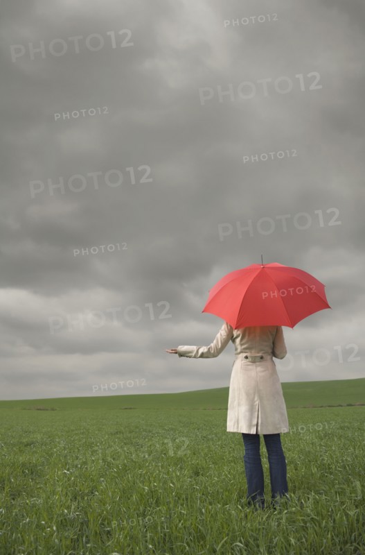 Rear view of woman holding umbrella in field