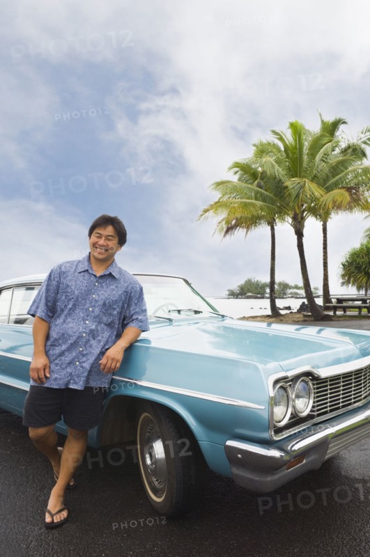 Asian man leaning on car