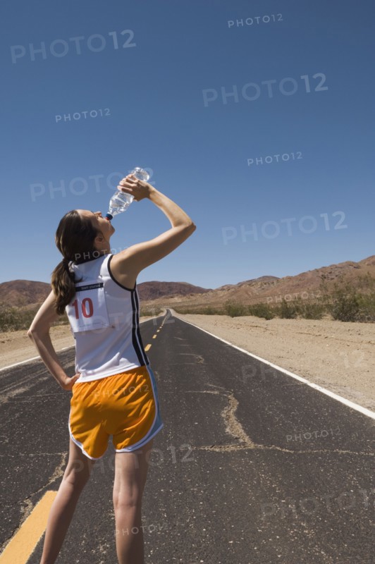 Mixed Race female runner drinking water