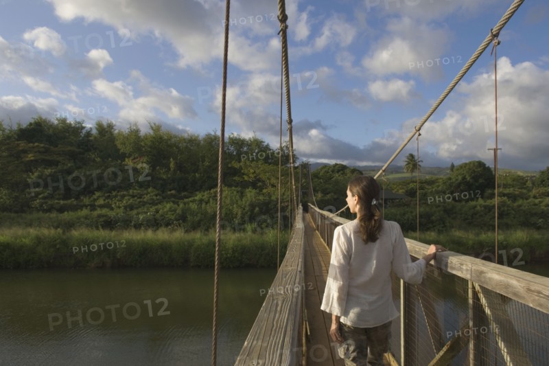 Rear view of woman walking on wooden footbridge