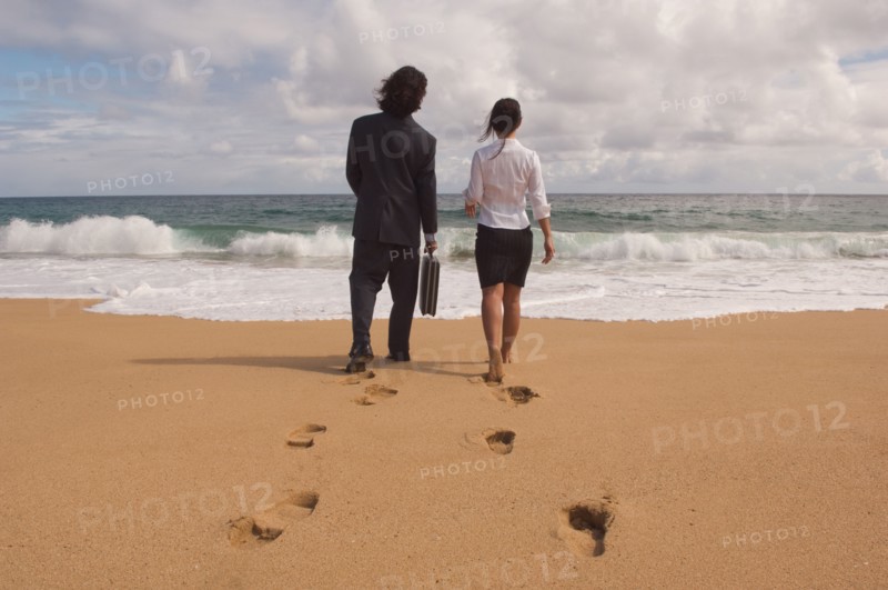 Businessman and businesswoman walking towards ocean