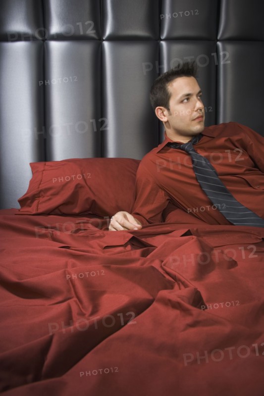 Man wearing shirt and tie on bed